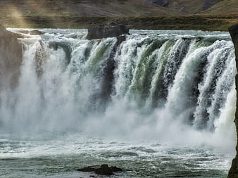 Powerful waterfall cascading into misty river pool