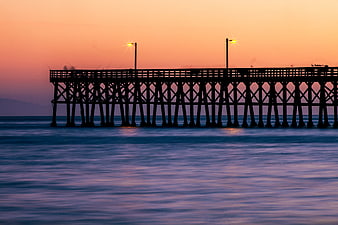 Silhouette of wooden pier at sunset over calm ocean