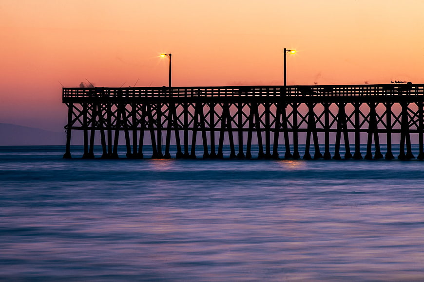 Silhouette of wooden pier at sunset over calm ocean