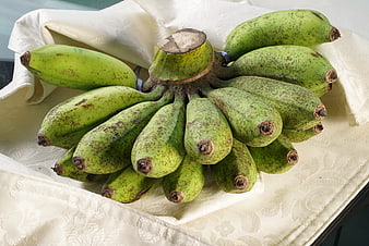 Bunch of green speckled bananas on white cloth