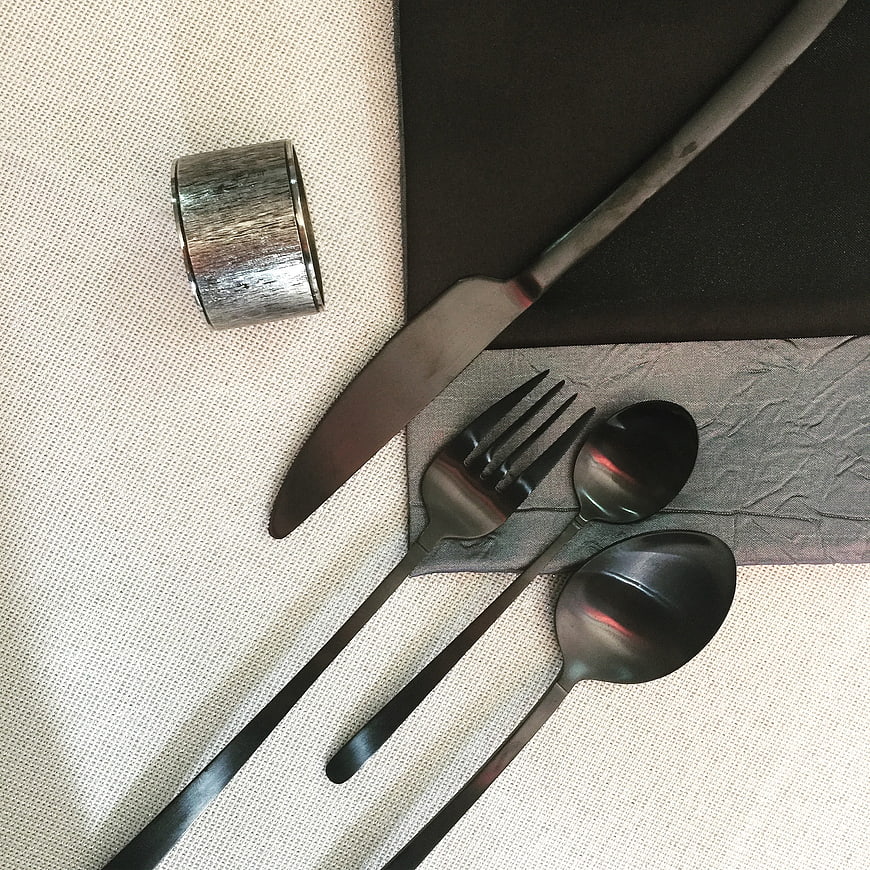 Black matte cutlery set on textured tablecloth