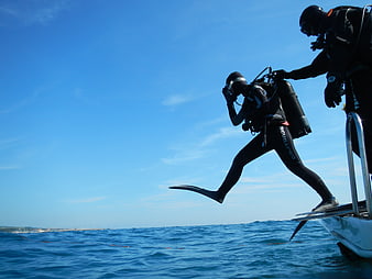 Scuba diver giant stride entry into blue ocean from boat