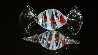 Glass candy sculpture with red and blue swirls on black background