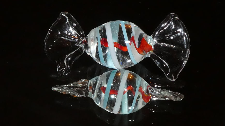 Glass candy sculpture with red and blue swirls on black background