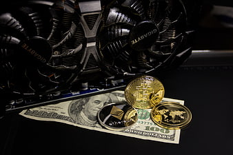 Cryptocurrency coins and dollar bill on a laptop with a Gigabyte GPU