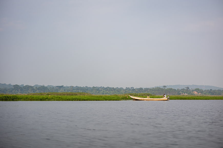 Small wooden boat with fishermen on calm river landscape