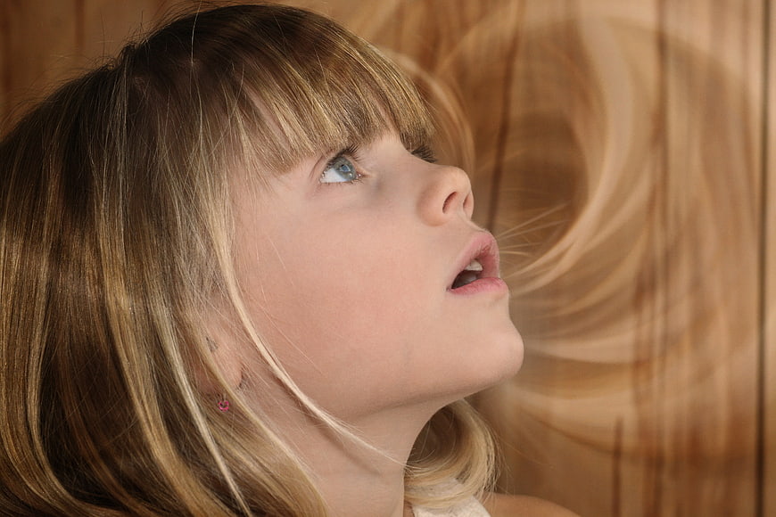 Close-up portrait of young girl looking up in wonder