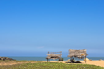 Rustic straw huts on a sandy beach with blue sky