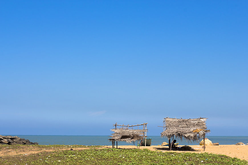 Rustic straw huts on a sandy beach with blue sky
