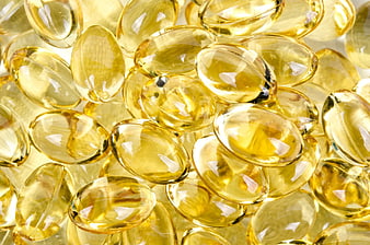 Close-up of translucent yellow gel capsules on white background