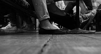 Low angle black and white photo of feet under a bar table
