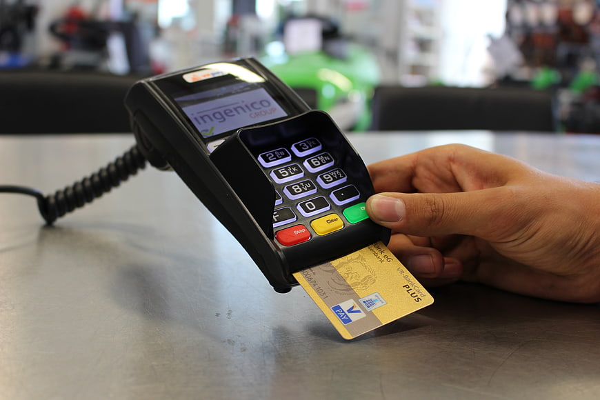 Hand inserting credit card into POS terminal for payment
