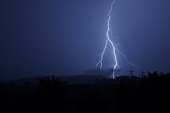 Dramatic Lightning Strike Over Dark Silhouette Landscape