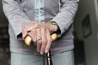 Close-up of elderly woman's hands holding a wooden walking stick
