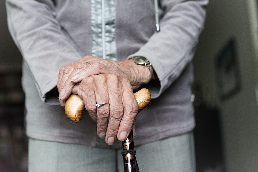 Close-up of elderly woman's hands holding a wooden walking stick