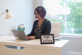 Woman with purple hair working on laptop in bright office