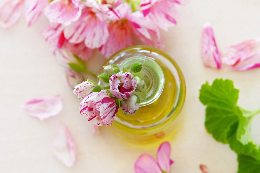 Top View of Essential Oil Bottle with Pink Geranium Flowers