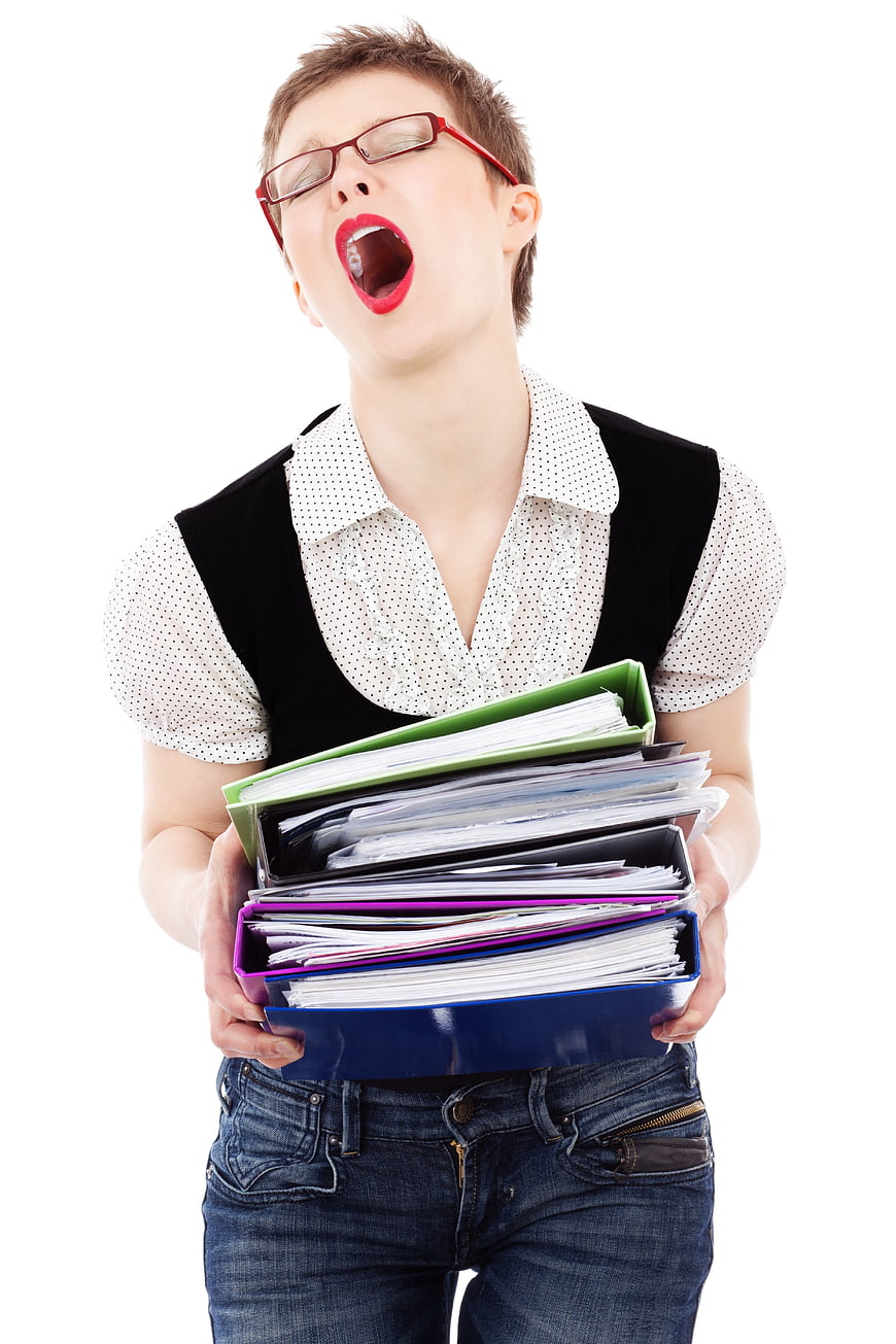 Exhausted businesswoman yawning with stack of colorful folders