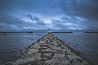 Lighthouse at End of Rocky Jetty Under Stormy Sky