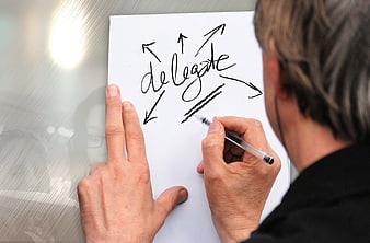 Man writing delegate with arrows on paper