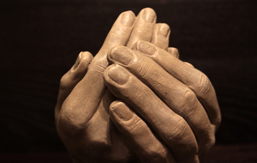 Clay Sculpture of Praying Hands on Dark Background