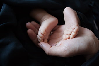 Close-up of newborn baby feet held in adult hand