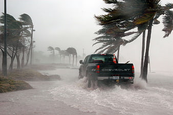 Black pickup truck driving through flooded road during hurricane