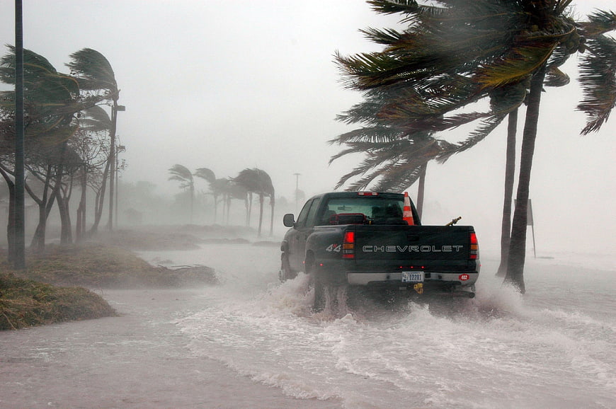Black pickup truck driving through flooded road during hurricane