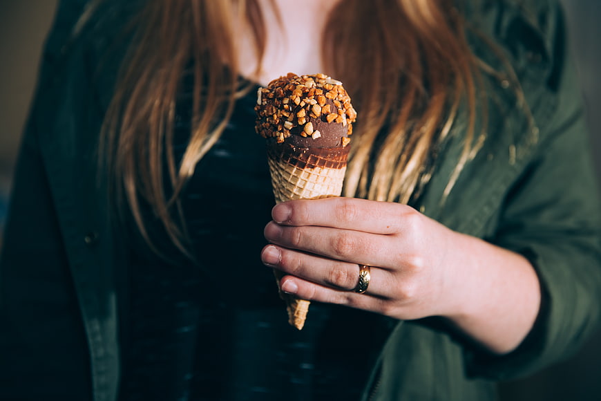 Woman Holding Chocolate Ice Cream Cone with Nuts