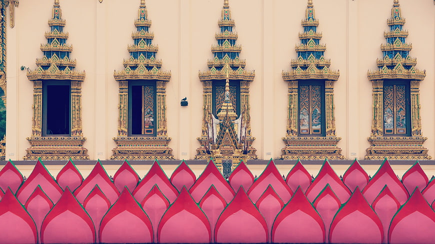 Thai temple facade with ornate golden windows and pink roof