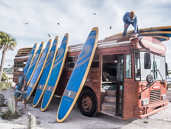 Vintage Surf Bus with Blue Boards on Sandy Beach