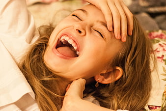 Close-up of laughing child with hand on forehead