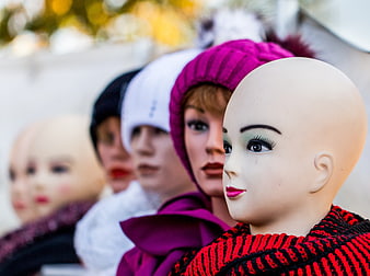 Mannequin heads wearing winter hats and scarves in a row