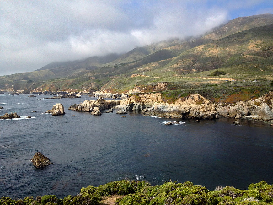 Scenic Rocky Coastline with Foggy Mountains and Ocean