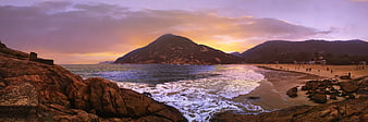 Panoramic Sunset at Rocky Beach with Mountain Backdrop