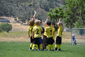Young soccer team huddle with coach on grass field