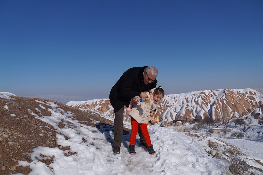 Grandfather and granddaughter playing in snow on mountain