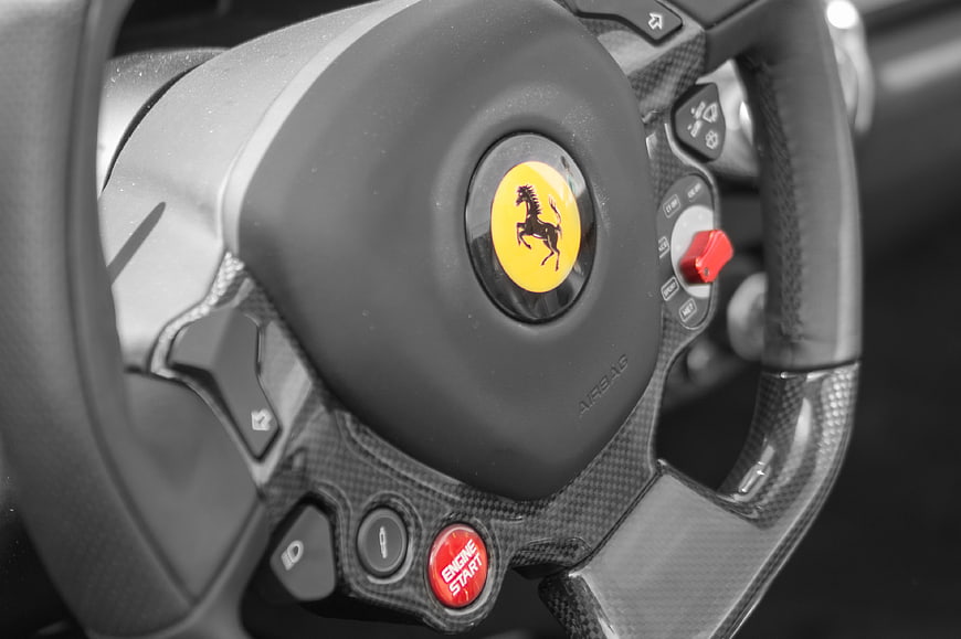 Close-up of Ferrari steering wheel with carbon fiber and engine start button