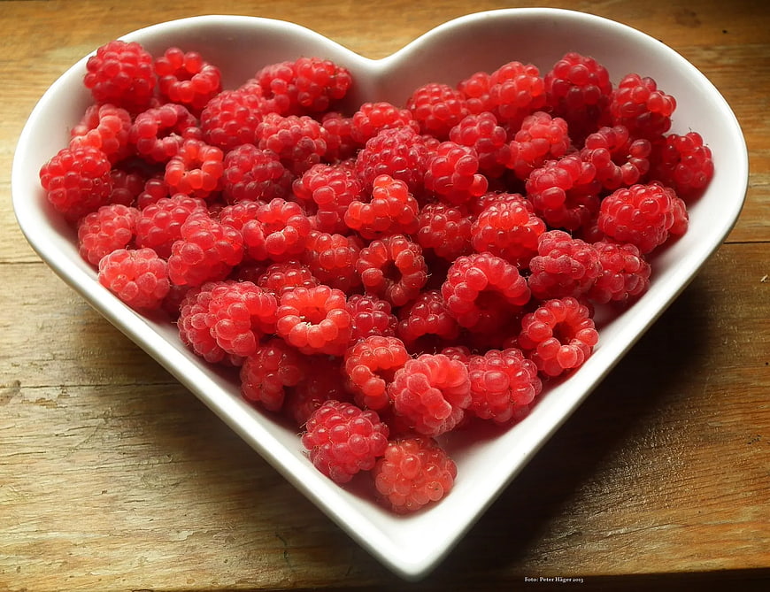 Fresh Raspberries in Heart-Shaped White Bowl on Wood