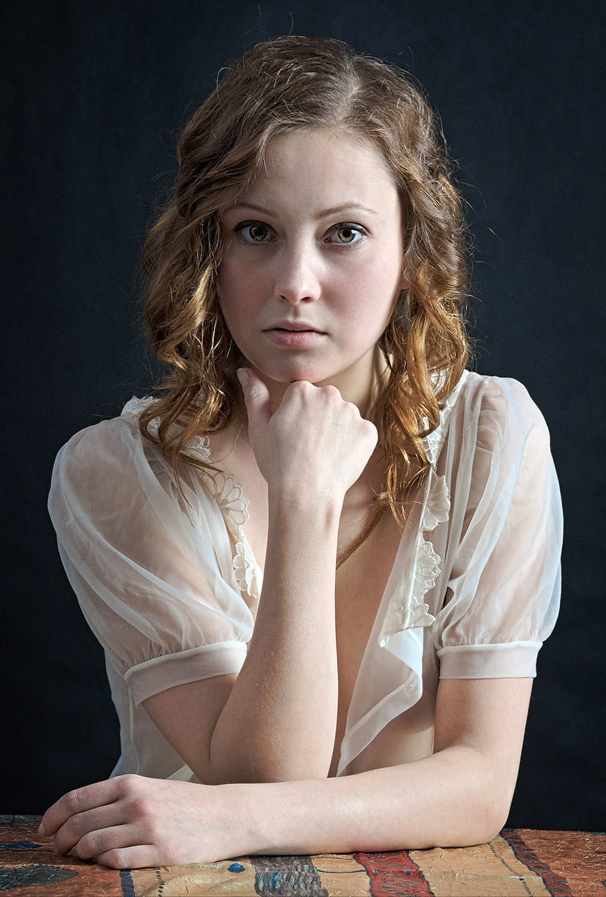 Thoughtful Portrait of Young Woman in White Sheer Blouse