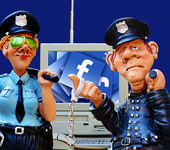 Police figurines with handcuffs and Facebook logo on computer screen