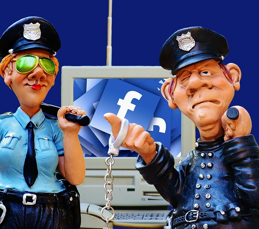 Police figurines with handcuffs and Facebook logo on computer screen