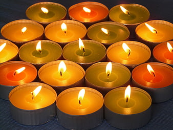 Colorful lit tea light candles arranged on blue textured surface