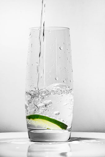 Refreshing glass of water with lime slice and pouring stream