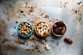 Top view of bowls with nuts and dried fruits on rustic metal