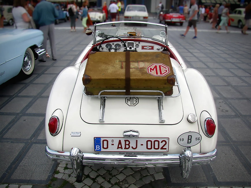 Rear View of White Classic MG Car with Vintage Suitcase