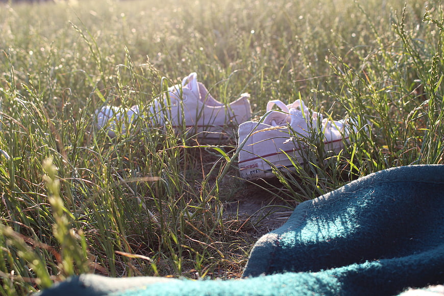 White sneakers in tall grass with blue blanket