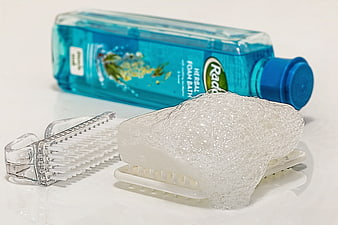 Blue Bath Foam Bottle And Soapy Nail Brush On White Surface