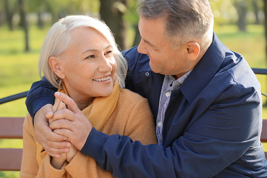 Happy Senior Couple Embracing on Park Bench