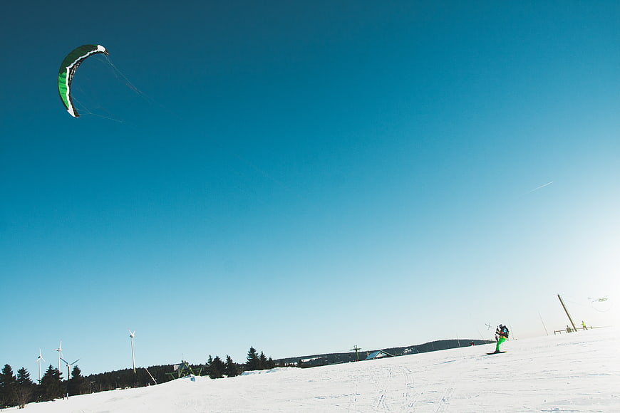 Snowkiting on a sunny winter day with blue sky